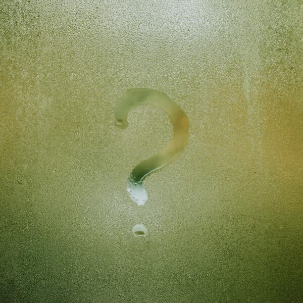 A question mark drawn on foggy glass, evoking curiosity and mystery.